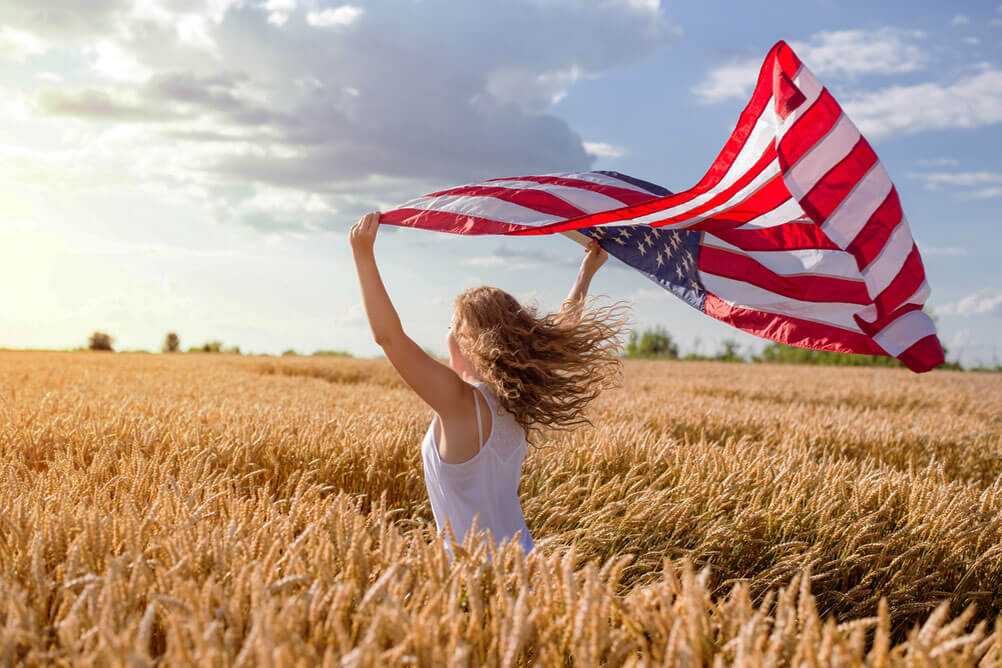 Woman running through cornfield waving American flag to celebrate Powerball winners