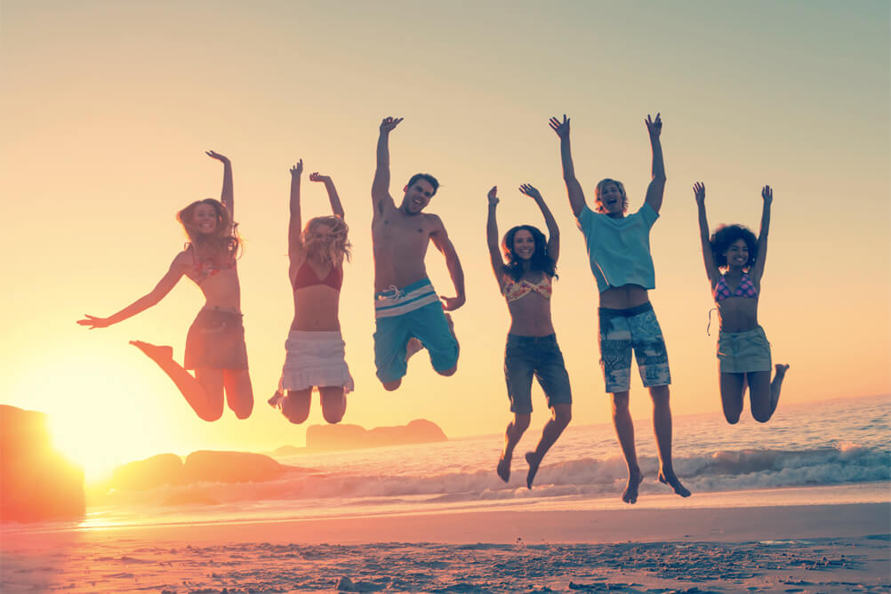 Group of six people jump into the air as the sun sets