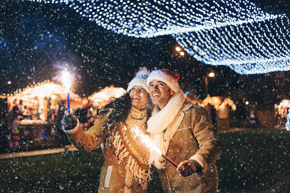 A couple celebrate Spanish Christmas in the snow under Christmas lights