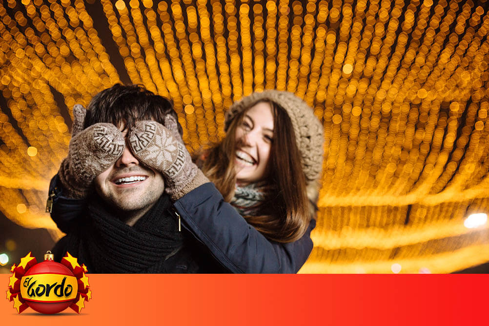 Young woman covers the eyes of her smiling boyfriend at Christmas time