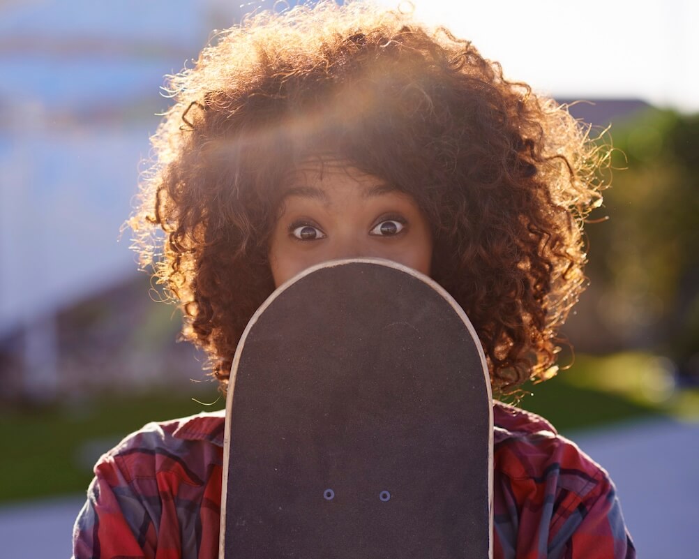 A woman, hiding some of her face behind a skateboard, shocked to discover the Martingale strategy does not work.